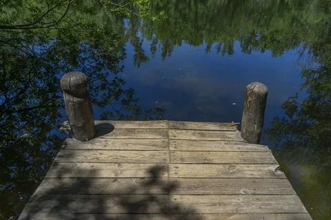 A rustic wooden pier surrounded by lush greenery and calm waters in the Bos.. Stock Photos