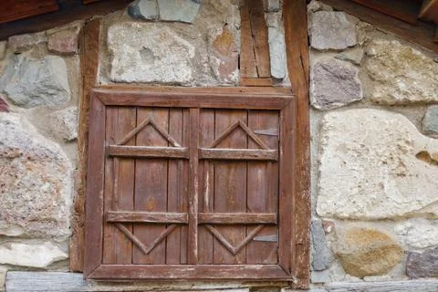 Rustic wooden shutter with geometric patterns on stone wall of traditional .. Stock Photos