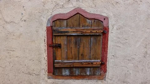 Rustic Wooden Shutter on an Old Stone Wall in a Historic Village, Daytime Stock Photos