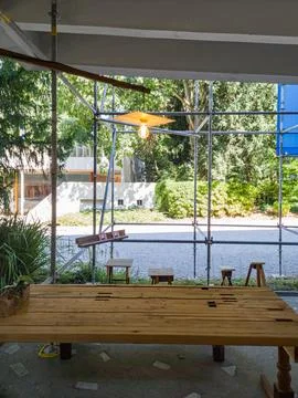 Rustic wooden table and stools sit beneath a scaffolding Stock Photos