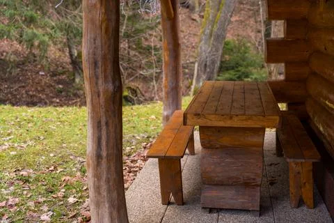 Rustic wooden table with two benches near a log cabin on a cloudy winter Stock Photos