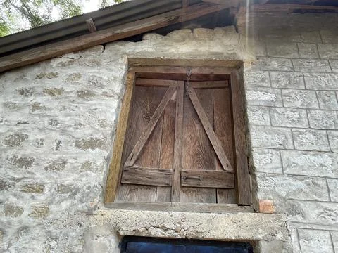 Rustic wooden window or hatch with Z-braced shutters set into a weathered s.. Stock Photos