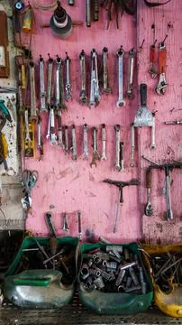 Rustic workshop tools organized on a pink wooden wall, featuring wrenches, .. 스톡 사진