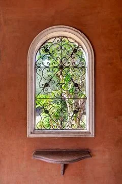 Rustic wrought iron window with marble shelf against vibrant red wall. The Stock-Fotos