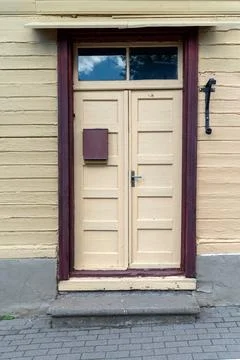 A rustic yellow door features a mailbox, framed by wooden siding on a sunny d Stock Photos