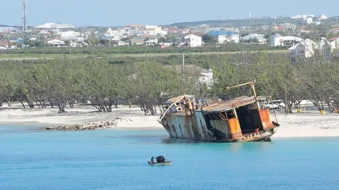 Rusting hulk of a shipwreck sits on the shore of Grand Turk. Видео 84699349