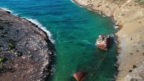 The rusting hull of a shipwreck in a small turquoise bay on the rocky coast of Stock Footage 346496134