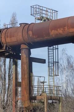 Rusting industrial machinery structure with large pipes against the sky Stock Photos