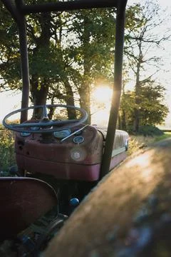 A rusting old tractor standing in a field on a summers evening. Stock Photos