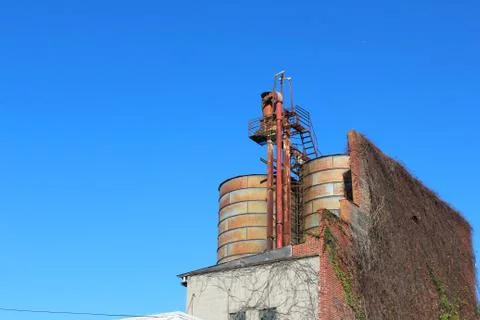 Rusting silos and brick facade against a blue sky Stock Photos
