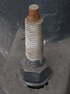 Rusting threaded bolt with hex nut on metal base Stock Photos