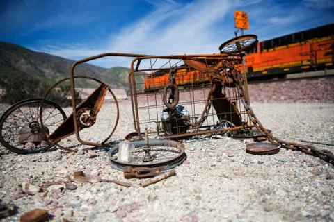 Rusty abandoned wheels and frame with train passing by Fotos Stock