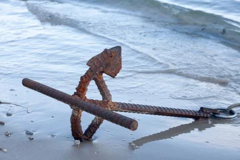 Rusty anchor on the beach. Stock Photos