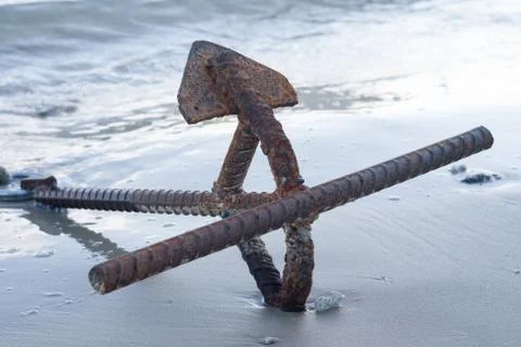 Rusty anchor on the beach. Stock Photos