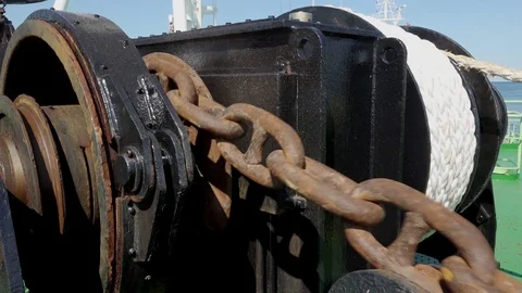 Rusty anchor chain moved by large black winch close view Stock Footage 118356940