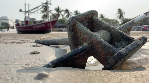 Rusty anchor on sandy beach close up shot. Old cast iron tie with fishing boat Video stock 195527668