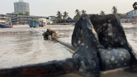 Rusty anchor on sandy beach close up shot. Old cast iron tie with fishing boat Video stock 195527865