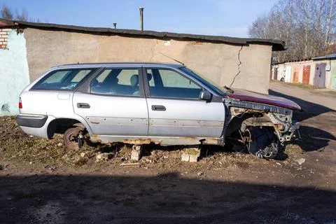 Rusty auto junk on the background of old garages. An old disassembled car in  Stock Photos