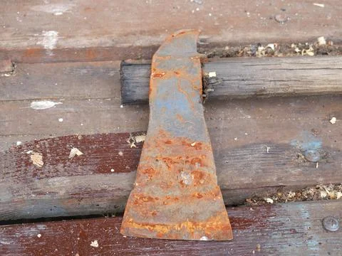 A rusty axe is lying on the table. The blade is clearly visible Stock Photos