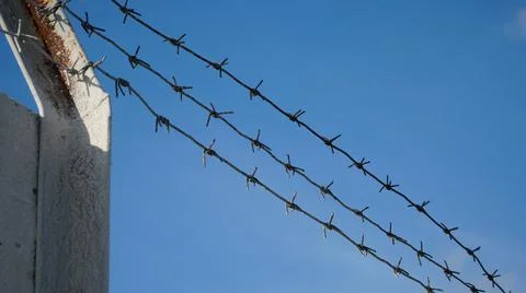 Rusty barbed wire against a cloudy sky. Serving a sentence behind barbed wire Stock Photos