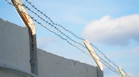 Rusty barbed wire against a cloudy sky. Serving a sentence behind barbed wire Stock Photos
