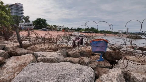 Rusty barbed wire coiled around large rocks Stock Footage 278642666