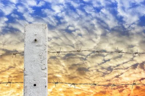 Rusty barbed wire fence with cloud and sky. Stock Photos