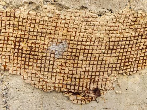 Rusty bare reinforcement in retaining wall with crumbling plaster patch 스톡 사진