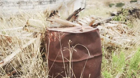 Rusty barrel is laying in dry grass and weeds Video stock 289663352