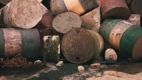 Rusty barrels stacked in a disorganized manner near an industrial site Stock Footage 306302597
