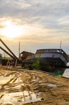 Rusty beached boat on a cloudy day against the sun Stock Photos