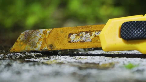 Rusty blade, yellow Olfa cutter knife on the ground, static close up shot. Stock Footage 133609528
