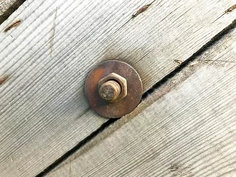 Rusty bolt with a nut in an old board. Stock Photos