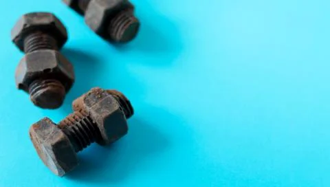 Rusty bolts and nuts made of chocolate isolated on sky blue background. Stock Photos