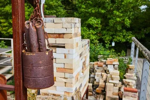 Rusty Bucket and Bricks at Construction Site with Greenery Background 스톡 사진