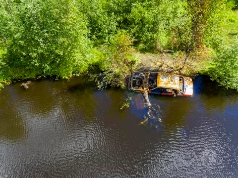 A rusty car frame in wild forest lake near the shore on summer day Stock-Fotos