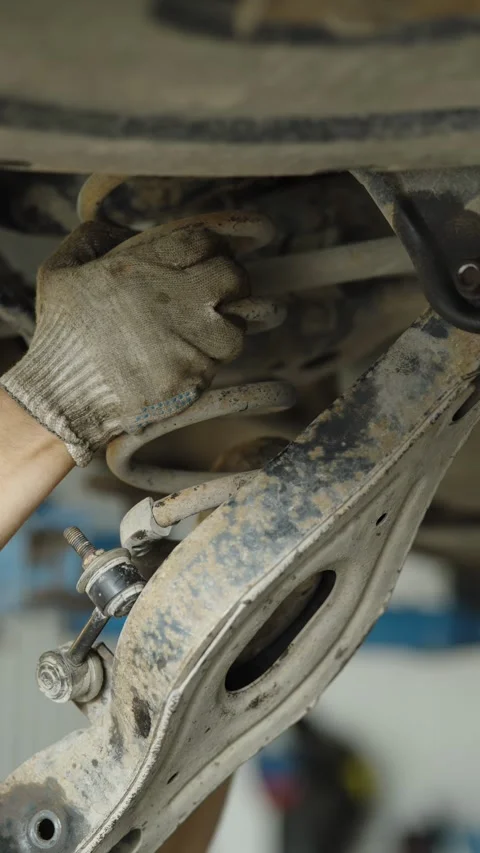Rusty car suspension coil spring and control arm undercarriage view Stock Footage 337570588