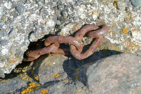 Rusty chain embedded in rocky surface, showcasing weathered textures Stock Photos