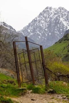 Rusty chain link fence with rotating wicket in mountains of Kyrgyzstan Photos