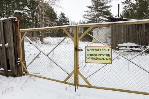 A rusty chain link gate with a yellow Russian restricted area Stock Photos