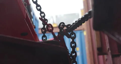 Rusty chains coil beside damp cargo containers on dock Stock Footage 321774034