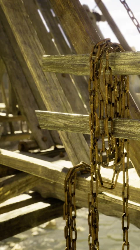 Rusty chains rest on weathered wooden beams in a quiet coastal setting Stock Footage 331834587