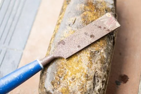 Rusty chisel on weathered sharpening stone Stock Photos