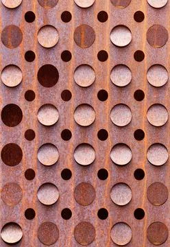 Rusty curly sheet of metal texture with round holes. Vertical image. Stock Photos