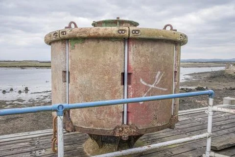 Rusty cylindrical structure stands on weathered wooden platform Stock Photos