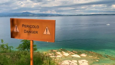 Rusty danger sign over the cliff in front a lake with a beautiful water Stock Footage 241147645