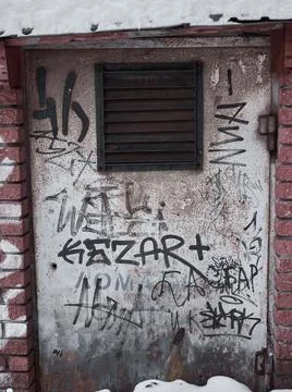Rusty door with bars. Painted with graffiti Stock Photos