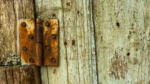 A rusty door hinge is currently resting on a wooden door surface Stock Photos