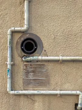 Rusty drain and grate surrounded by worn pipes Stock Photos