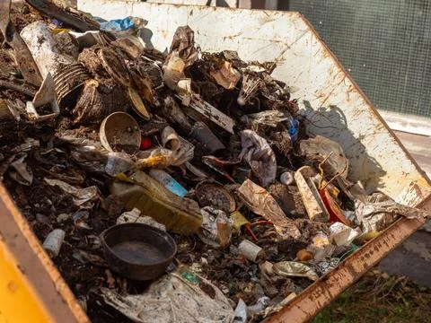 Rusty Dumpster Filled with Soil and Mixed Plastic Waste Stock Photos